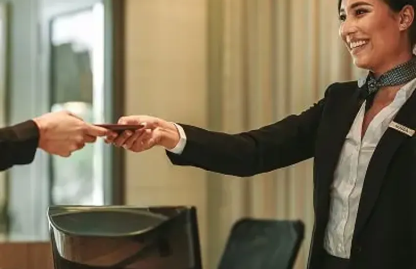 Woman receiving a document from a guest at a reception or service desk.